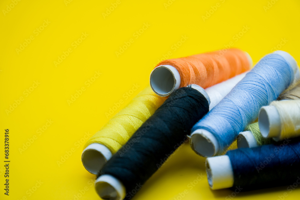Colorful sewing threads on yellow background Colorful sewing threads on yellow background