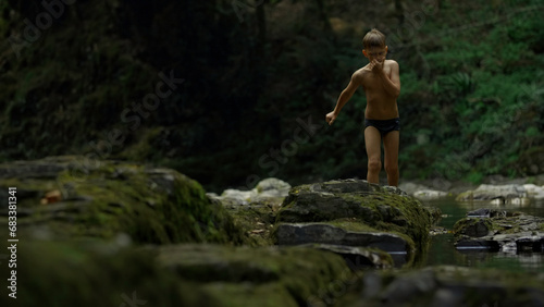 Boy walking on mossy rocks on green hills background. Creative. Teenager boy in jungles.