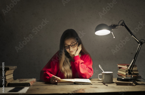 young woman studies with the light of a lamp