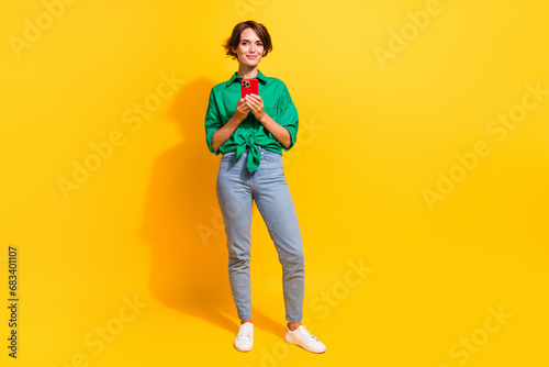 Full length photo of positive cute lady wear green shirt chatting instagram twitter telegram facebook isolated yellow color background