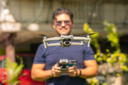 A middle aged man operating a small aerial drone hovering outside his home. A typical hobbyist operator.