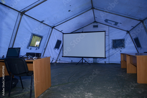 Interior of the mobile headquarter of State Rescue Service deployed for an accident case, training. Laptops, tables, large screen under the tent.