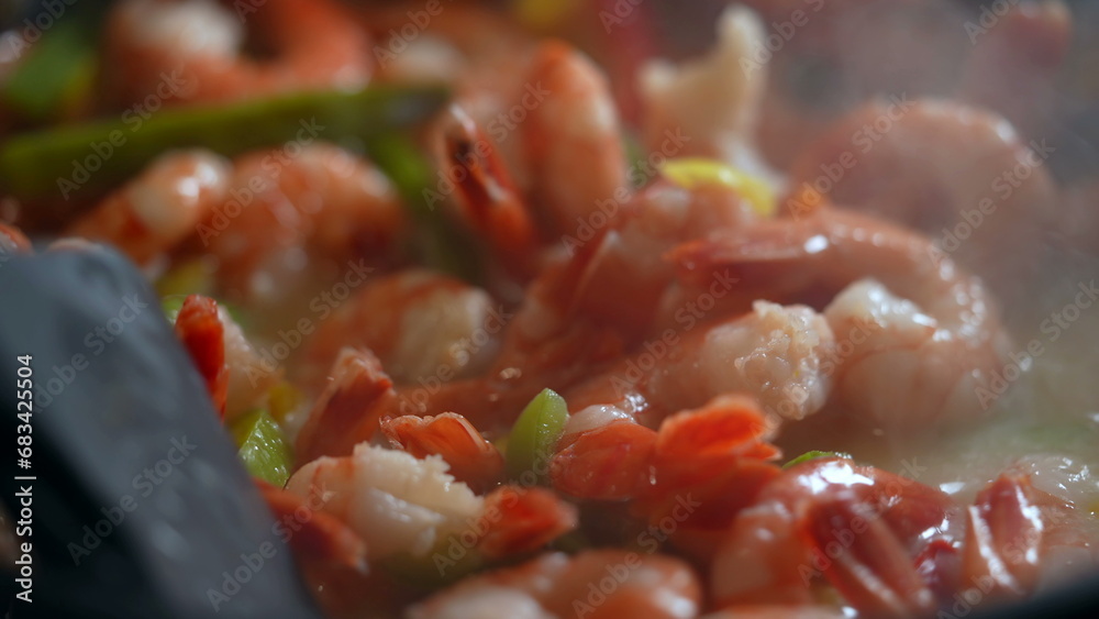Cooking shrimps and vegetables inside pan, stirring food and preparing meal macro close-up Cooking shrimps and vegetables inside pan, stirring food and preparing meal macro close-up