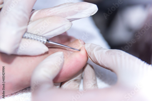 close up of pedicure in salon, removing cuticles, man's foot