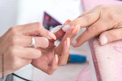 Close-up of a woman in a nail salon, a beautician cuts her cuticles, Woman getting a manicure in a spa center. 