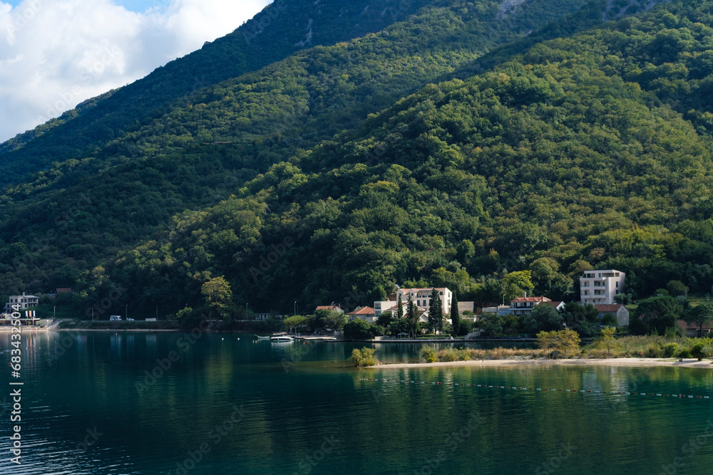 nature landscape of Boka Kotorska Bay in Montenegro, stunning green mountains, adriatic sea, stone houses, sailing boats, calm water with reflections