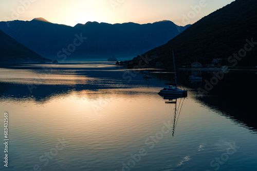 nature landscape of Boka Kotorska Bay in Montenegro, stunning green mountains, adriatic sea, stone houses, sailing boats, calm water with reflections at sunrize time photo