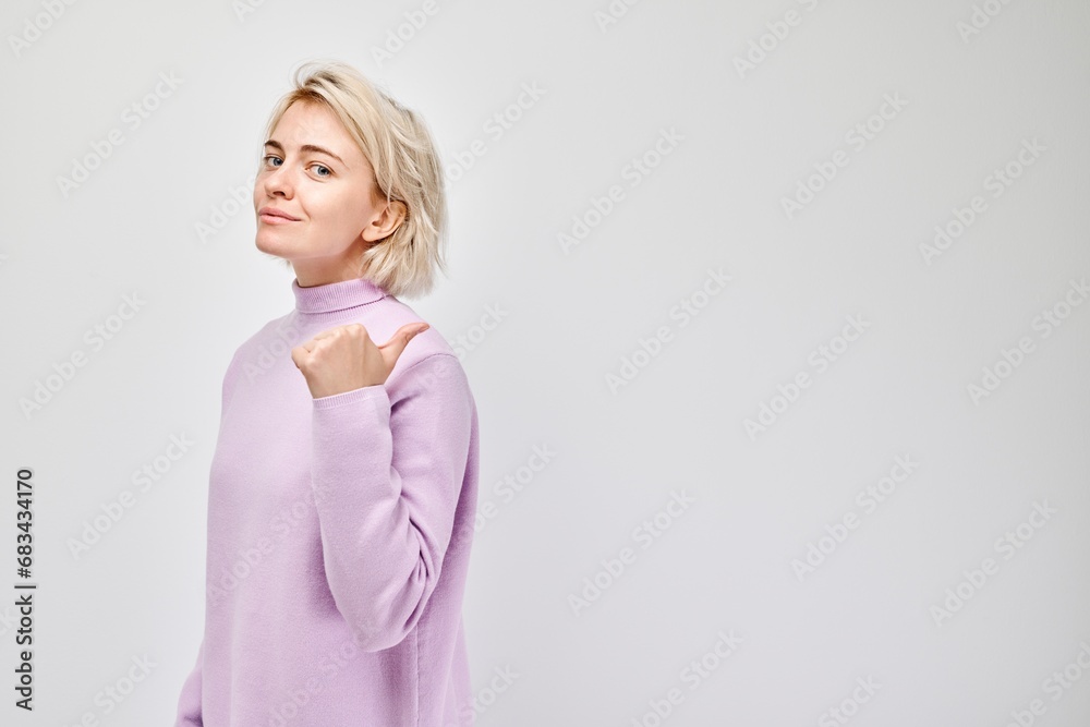 Young blond woman in casual pointing aside finger, demonstrating empty space for product or text isolated on white studio background. Young blond woman in casual pointing aside finger, demonstrating empty space for product or text isolated on white studio background.
