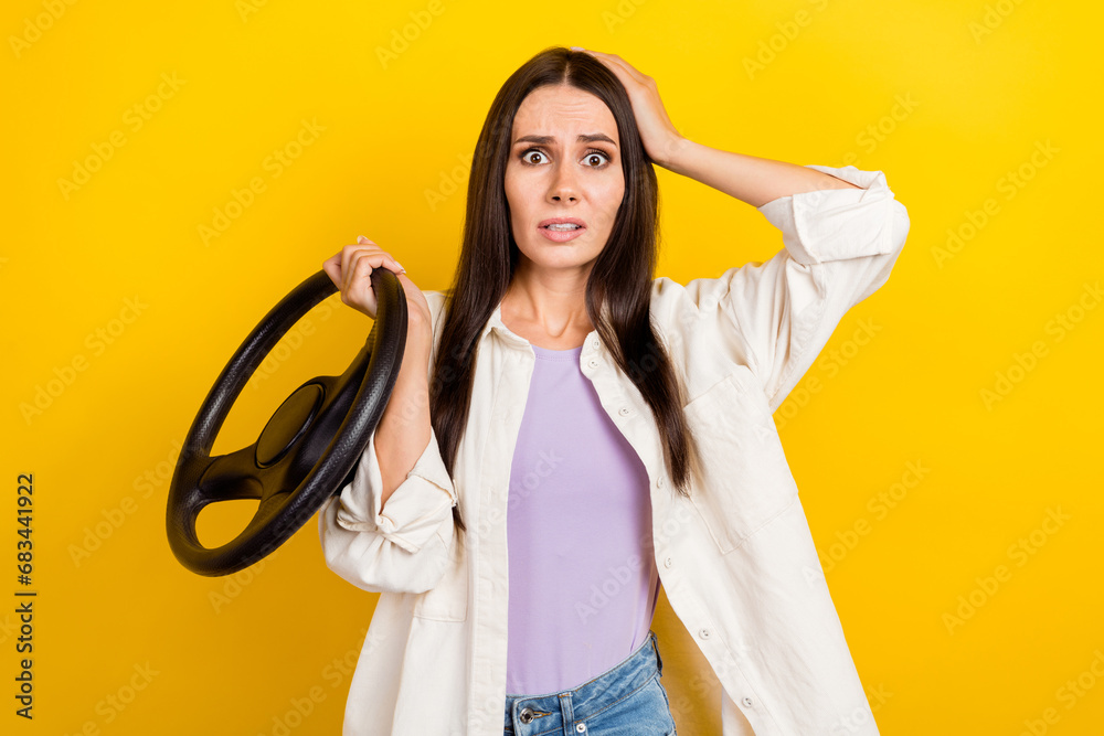 Photo of nervous astonished woman with long hair dressed white jacket hold steering wheel arm on head isolated on yellow color background Photo of nervous astonished woman with long hair dressed white jacket hold steering wheel arm on head isolated on yellow color background