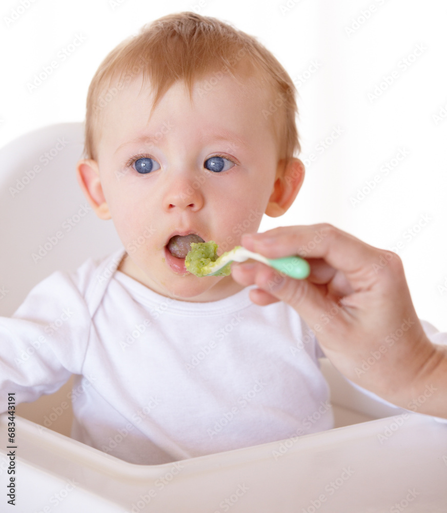 Sweet, spoon and baby eating vegetables in feeding chair in a studio for health and nutrition. Cute, natural and boy newborn, child or kid enjoying a meal for wellness diet by white background. Sweet, spoon and baby eating vegetables in feeding chair in a studio for health and nutrition. Cute, natural and boy newborn, child or kid enjoying a meal for wellness diet by white background.