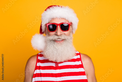 Photo of positive good mood senior guy dressed christmas swimwear hat glasses enjoying vacation isolated yellow color background