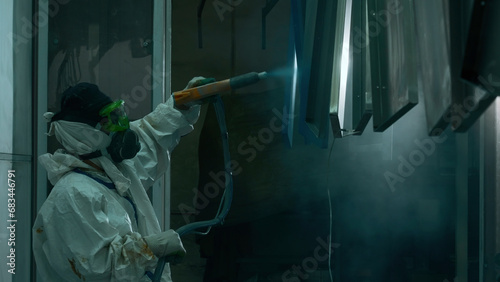 A worker coats a metal part with a powder coating using a spray gun. Creative. Powder coating of metal products, factory powder coating of metal structures.