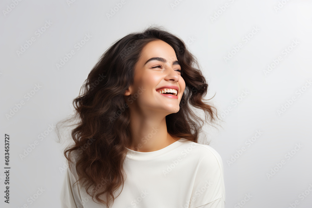 Happy young woman looking away with a smile while standing in a studio background Happy young woman looking away with a smile while standing in a studio background