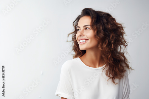 Happy young woman looking away with a smile while standing in a studio background