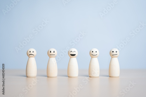 A happy smiling wooden figure stands in the center among many state emotion figures. Individuality, Unique person. Think positive, Pleasure, Feedback rating, Service review. World Mental Health Day