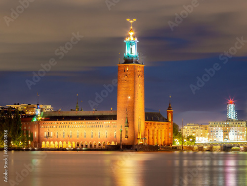 The building of the stone Stockholm City Hall on the shore of the strait. © pillerss
