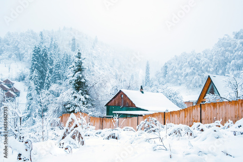 Winter village at the foot of the snowy mountains in winter fairy tale during snowfall