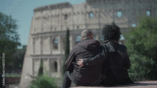 Romantic couple on honeymoon trip to Rome, Italy hug and kiss signtseeing Colosseum arena, selective focus slow motion shot photo