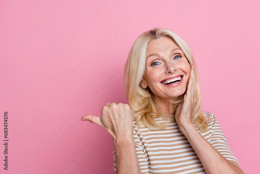 Portrait of ecstatic impressed woman wear trendy clothes directing at empty space logo arm on cheekbone isolated on pink color background Portrait of ecstatic impressed woman wear trendy clothes directing at empty space logo arm on cheekbone isolated on pink color background