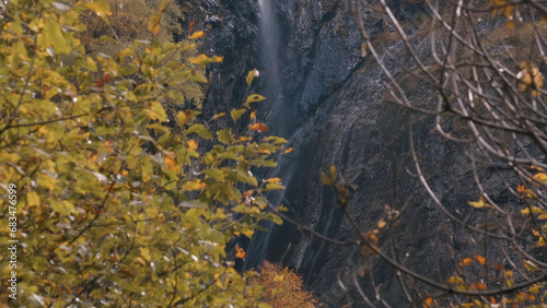 Waterfall surrounded by autumn trees and colorful vegetation. Creative. National park, mountain slope and water stream.