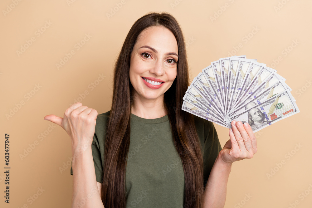 Photo of happy winner in casino lottery girl hold jackpot money direct finger empty space promo code isolated on beige color background Photo of happy winner in casino lottery girl hold jackpot money direct finger empty space promo code isolated on beige color background
