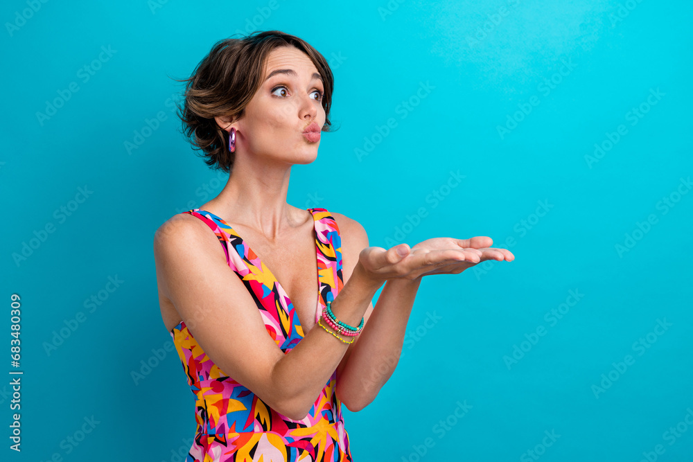Portrait of good mood gorgeous person with bob hairdo wear colorful dress send air kiss to empty space isolated on blue color background