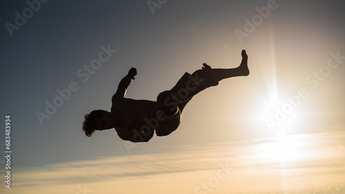 athletic young guy silhouette backflip in sunset
