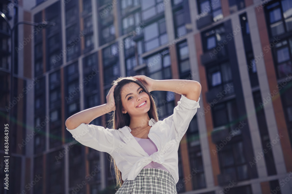 Fototapeta premium Portrait of peaceful friendly girl beaming smile hands touch hair enjoy warm sunny weather downtown outside