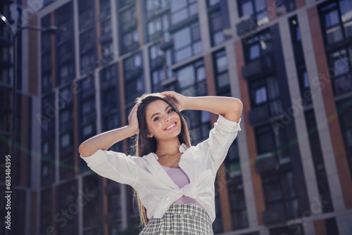 Portrait of peaceful friendly girl beaming smile hands touch hair enjoy warm sunny weather downtown outside