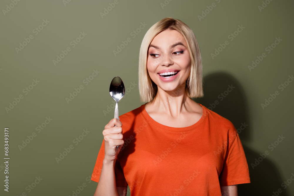 Photo portrait of pretty young girl hold look interested spoon dressed stylish orange outfit isolated on khaki color background Photo portrait of pretty young girl hold look interested spoon dressed stylish orange outfit isolated on khaki color background