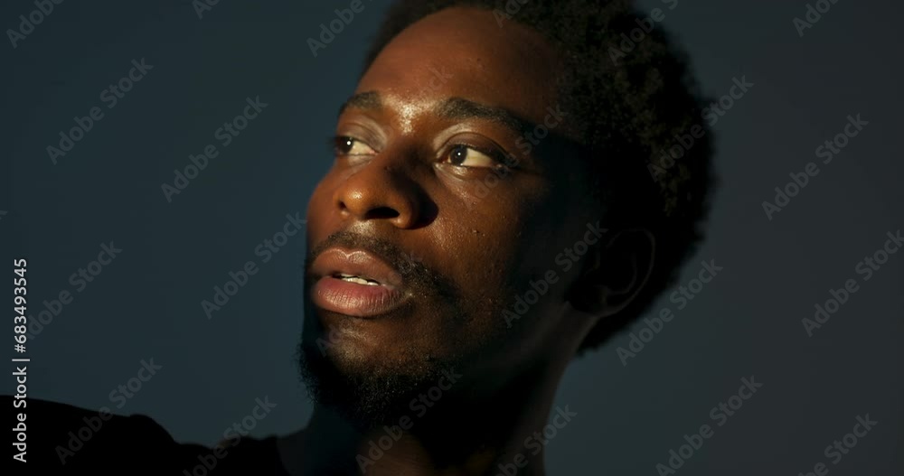Dark skined male young man looking at bright light standing in studio isolated playing with nulticolour light posing for camera. Well kept man with serious emotions art asthetic concept. Dark skined male young man looking at bright light standing in studio isolated playing with nulticolour light posing for camera. Well kept man with serious emotions art asthetic concept.