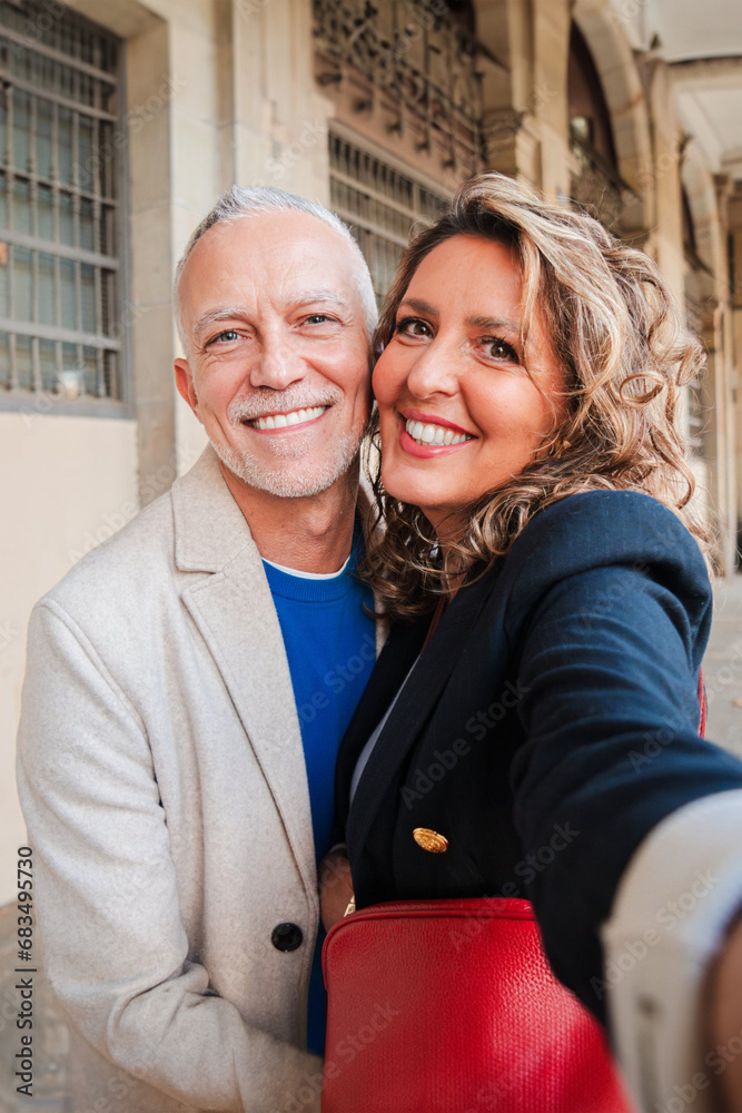 Vertical. Affectionate mid adult married couple having fun taking a selfie portrait together on a romantic date. Real middle aged friends smiling and laughing. Gray hair husband and wife on weekend Vertical. Affectionate mid adult married couple having fun taking a selfie portrait together on a romantic date. Real middle aged friends smiling and laughing. Gray hair husband and wife on weekend