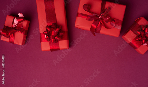 Boxes packed in red paper and tied with ribbon on a red background, gifts