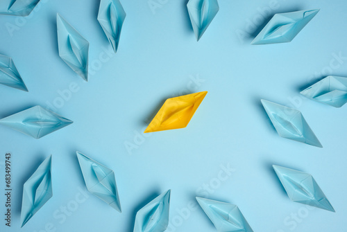 A group of blue paper boats surrounded one yellow boat, the concept of bullying, search for compromise. photo