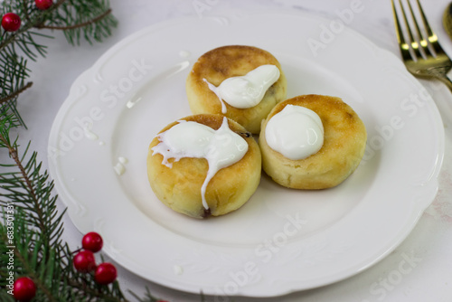 Delicious cheesecakes with sour cream. Breakfast on a white plate among spruce branches