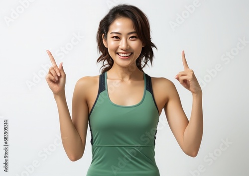 portrait of a expression of a happy sport woman dressed sportwear tanktop, against white background who holds her index finger up to explain or point, photo