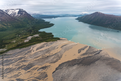 Ukak River flows into liuk Arm Naknek Lake in Katmai National Park, Alaska. Aerial view of river tan with suspended ash from Valley of Ten Thousand Smokes empties into glacial blue fresh water lake.  photo