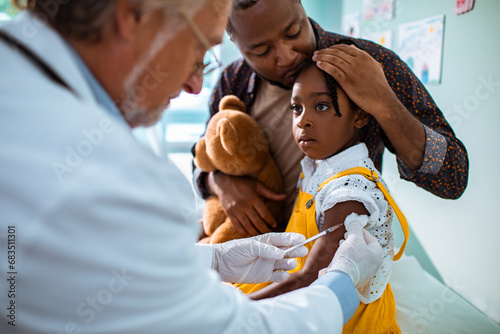 Doctor vaccinating little girl patient at clinic photo