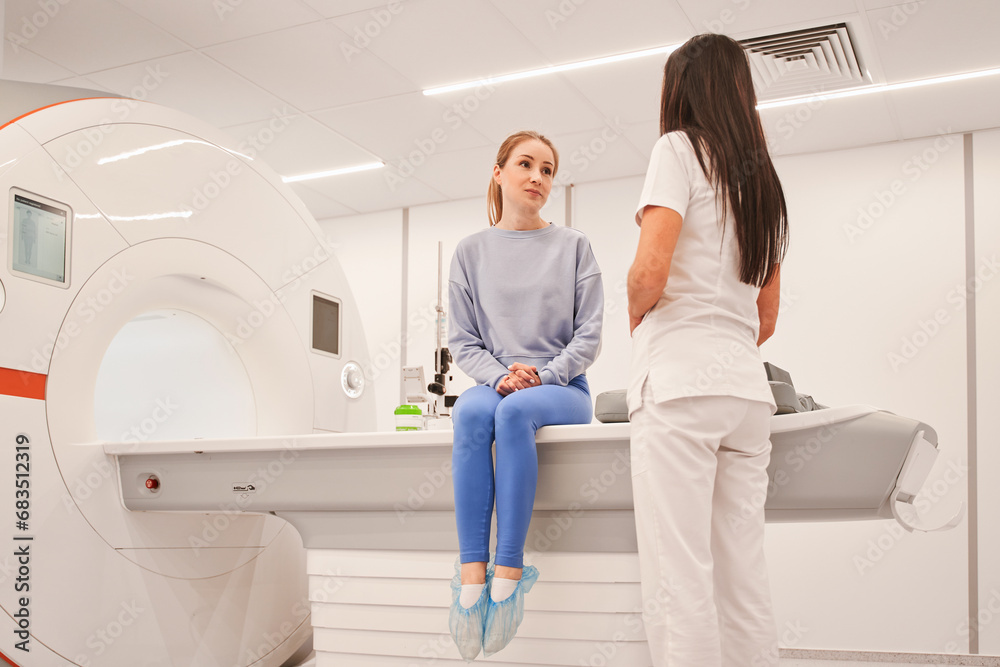 Female patient talking with woman doctor in the modern MRI Scan hospital laboratory Female patient talking with woman doctor in the modern MRI Scan hospital laboratory