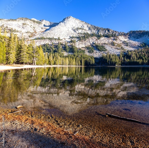 Californian Sierra Nevada Granite Mountain Peak Reflection in Treelined Tenaya Lake Calm Water. Scenic Vertical Portrait Panorama, Yosemite National Park, California USA photo