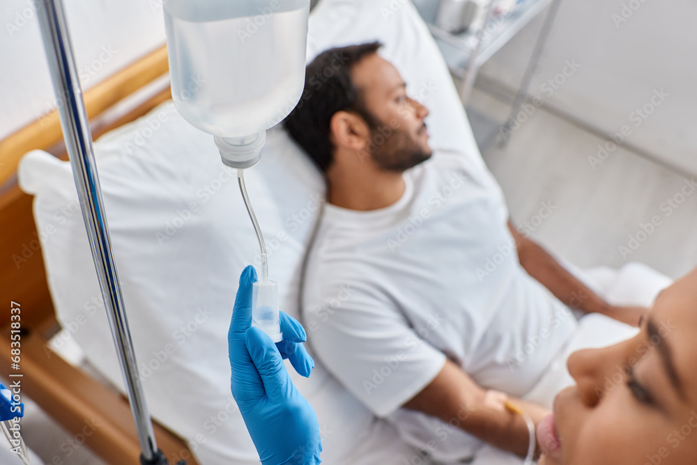Obraz premium focus on african american nurse setting drop counter next to her blurred indian male patient