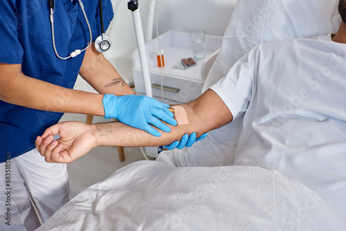 cropped view of african american nurse inserting catheter into arm of her indian patient  healthcare