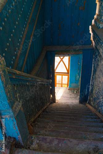Old abandoned dirty wooden staircase in empty building with blue wooden walls