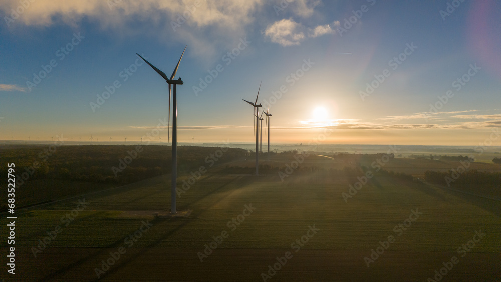 Windmills at Sunrise Amidst Misty Fields