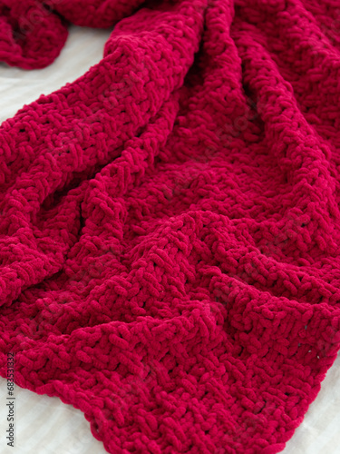 Red knitted plaid close-up. Background. Creases on soft surfaces.