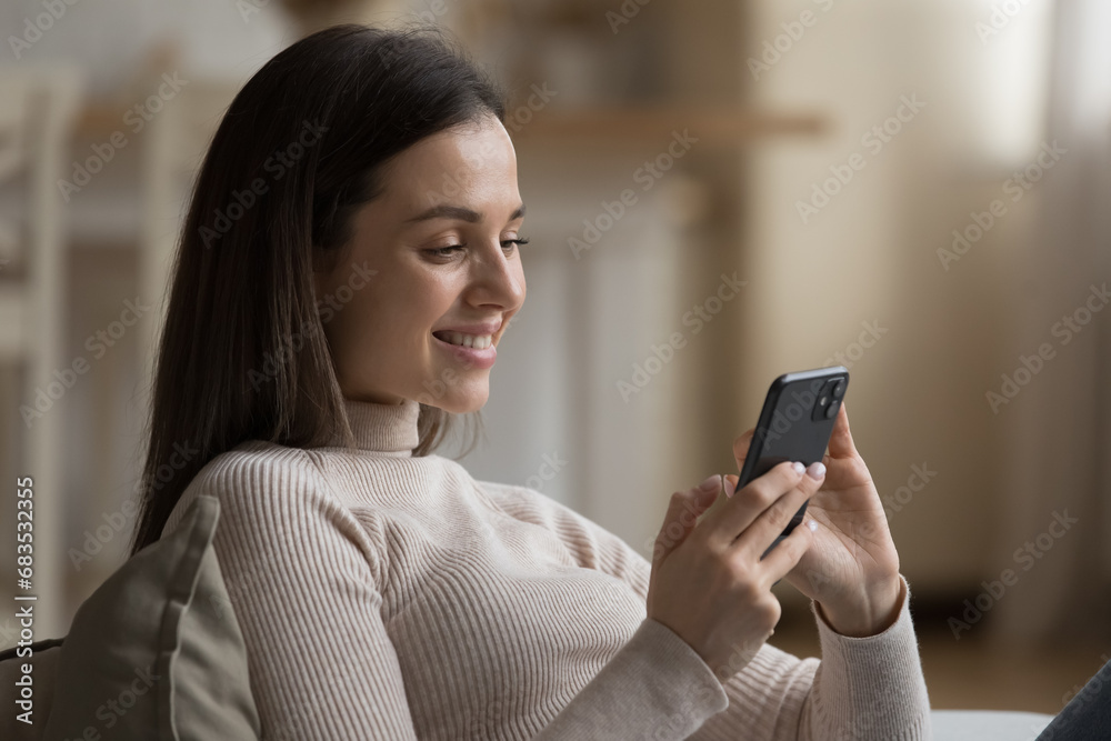 Young smiling woman spend leisure alone at home using modern smartphone browse web page, chatting via social networks enjoy distance communication. E-date on-line services for singles, tech concept Young smiling woman spend leisure alone at home using modern smartphone browse web page, chatting via social networks enjoy distance communication. E-date on-line services for singles, tech concept