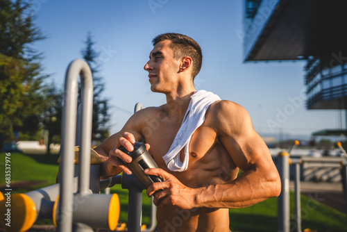 One caucasian man young male athlete take a brake during outdoor training in the park outdoor gym hold supplement shaker in hand happy confident strong copy space