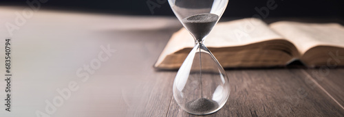Bild auf Leinwand Hourglass countdown with a book