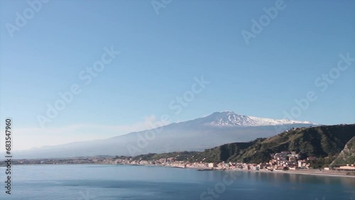 taormina sicily italy mount mt etna volcano giardini naxos shot from mountain high vantage point wide shot with pan left to right ending on homes buildings on mountain cliff photo