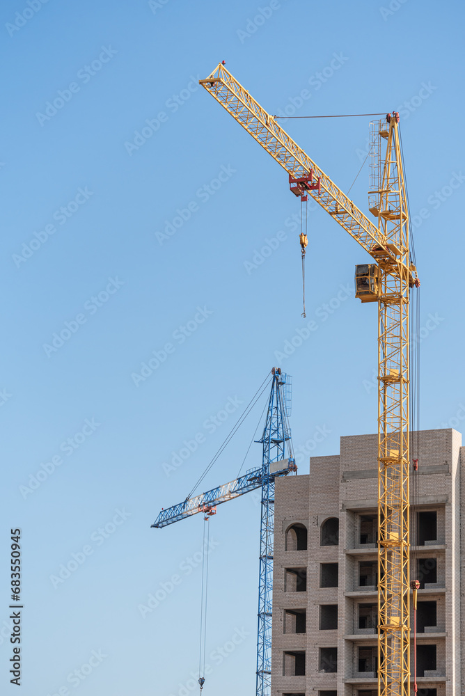 A construction site with a tower crane erecting a new house. A construction site with a tower crane erecting a new house.